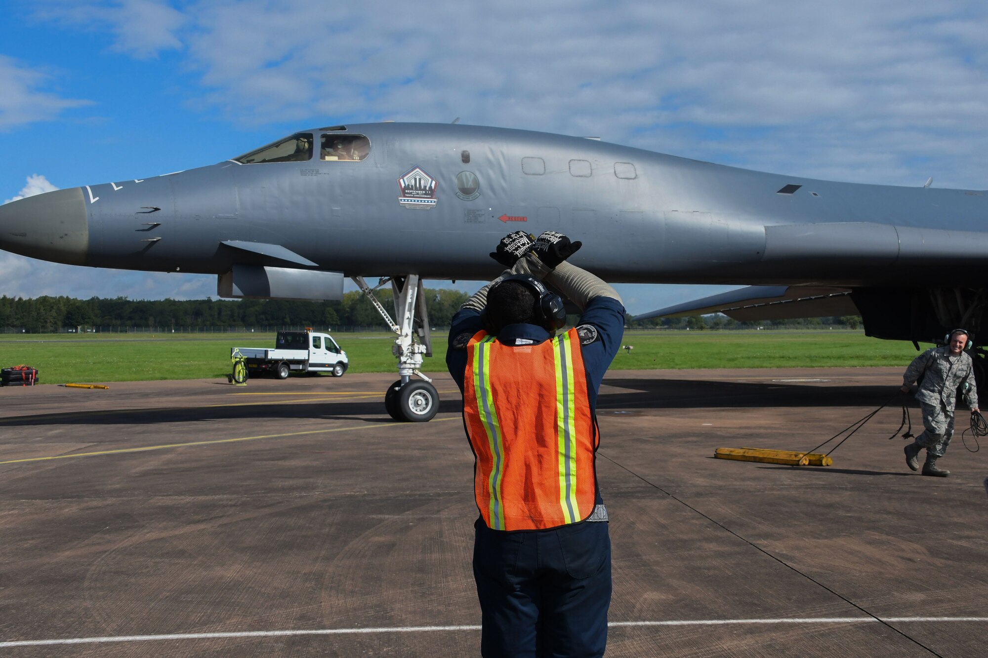 U.S. Air Force Staff Sgt. Ryan Branch, a 489th Bomb Group crew chief, signals pilots while Tech. Sgt. Bret Reeves, 489th BG crew chief, removes the chocks from a B-1 Lancer at RAF Fairford, U.K., Aug. 31, 2017.