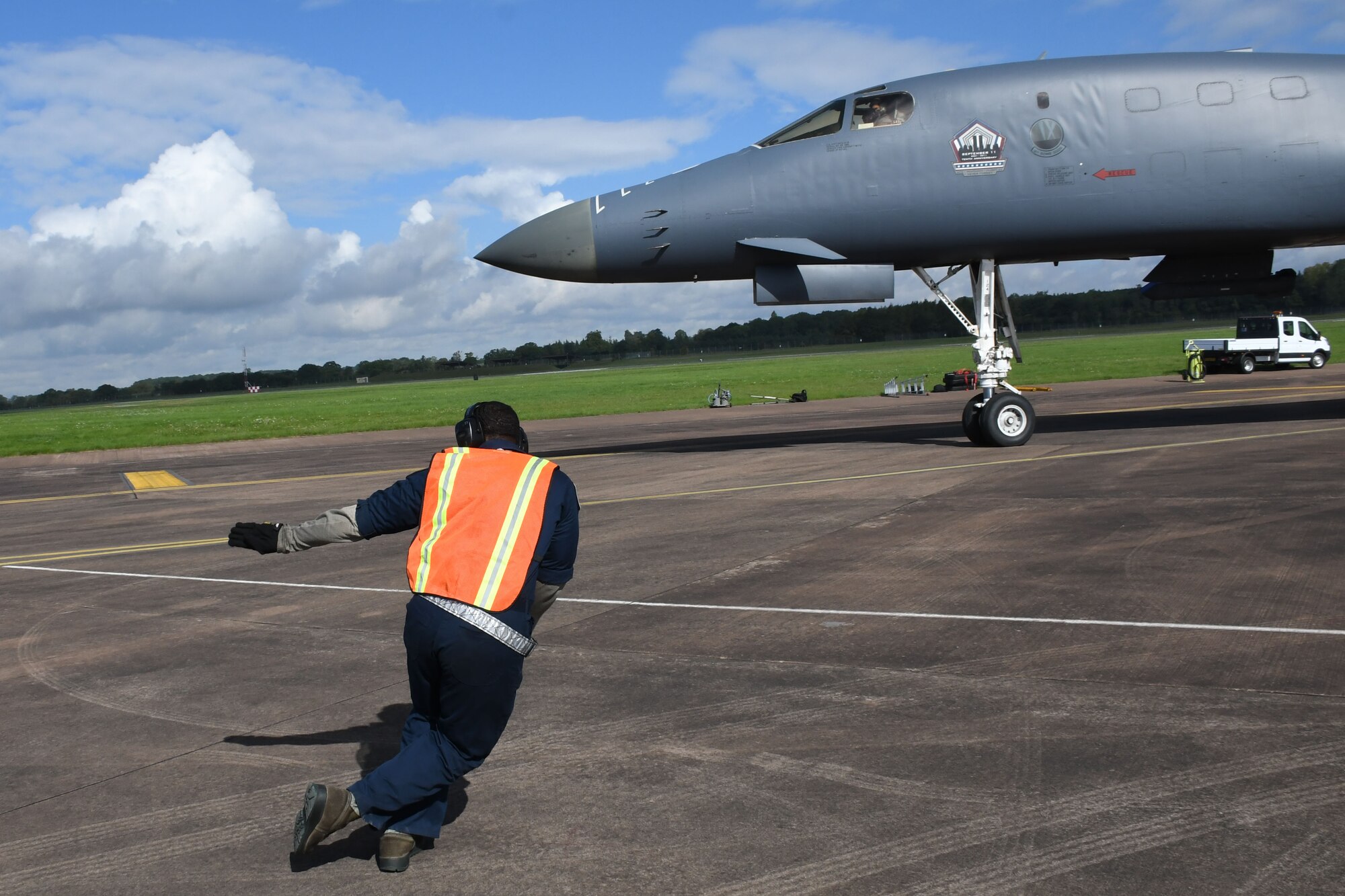 U.S. Air Force Staff Sgt. Ryan Branch, a 489th Bomb Group crew chief, marshals a B-1 Lancer to the taxiway at RAF Fairford, U.K., Aug. 31, 2017.