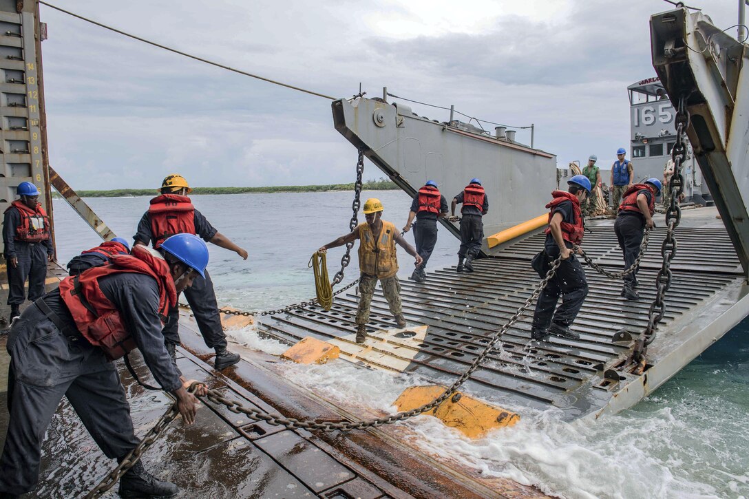 Sailors use chains to connect a landing craft to a ship's well deck.