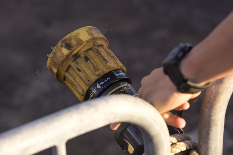 A U.S. Marine with Aircraft Rescue and Firefighting, starts a water hose to wash the salt water off race participants during the Tradewind Triathlon at the flight line aboard Marine Corps Air Station (MCAS) Kaneohe Bay, Aug. 27, 2017. The Tradewind Triathlon involves a 500 meter swim in Kaneohe Bay, a 13 mile bike ride on the MCAS Kaneohe Bay flight line, and a 3 mile run around the base. The event is part of the Commanding Officer Race Series and is open for the public to participate in. (U.S. Marine Corps photo by Lance Cpl. Isabelo Tabanguil)