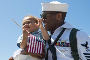 Four children in military uniforms participate in a ceremony.