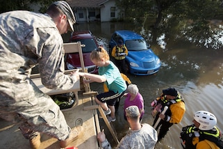 Service members help people into a military vehicle.
