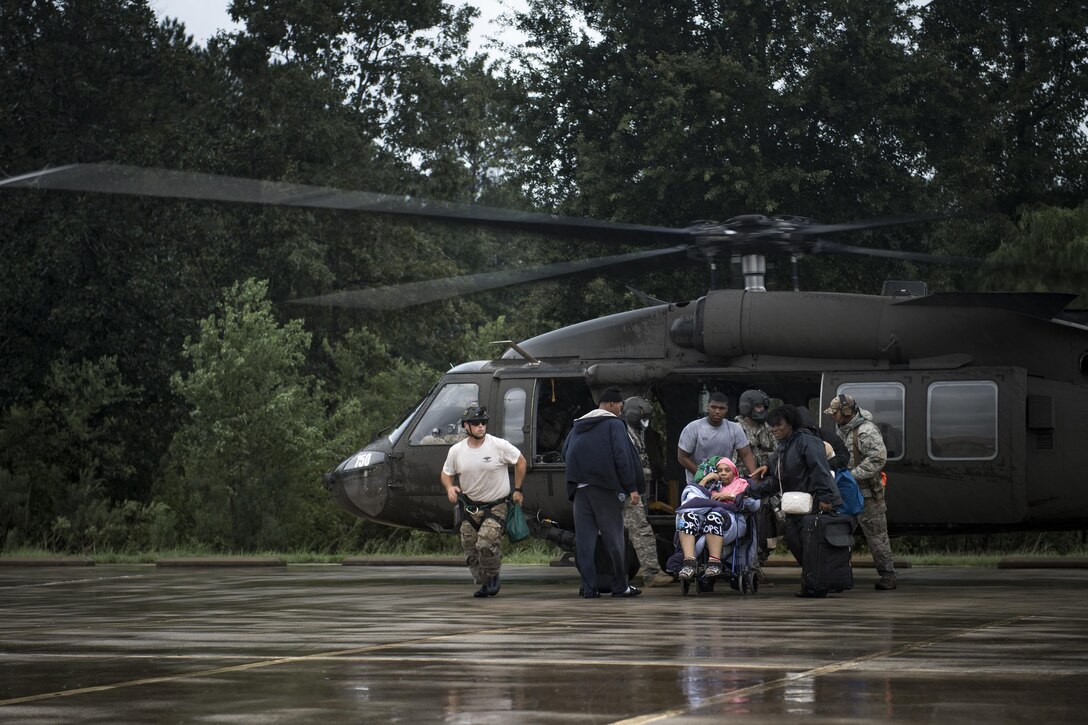 Airmen and Soldiers assist victims out of a UH-60 Black Hawk, Aug. 30, 2017, at the Orange County Convention and Expo Center in Orange, Texas.