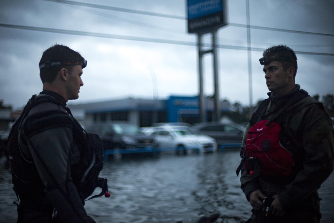 Pararescuemen from the 58th Rescue Squadron strategize outside of a flooded car dealership in Orange, Texas, Aug. 30, 2017.