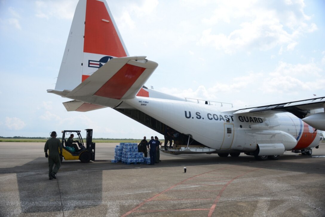 A Coast Guard aircrew loads bottled water onto an HC-130 Hercules aircraft.