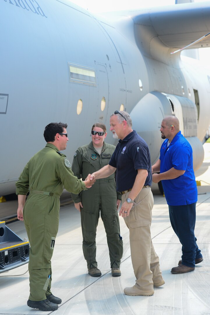 Mr. Scott Thomas, Federal Emergency Management Agency  Director of Hurricane Harvey Relief Efforts in Texas (center right), greets Royal Canadian aircrew pilot Capt. Daniel Ebisuzaki (left) and U.S. Air Force pilot Maj. Kimberley Sercel (middle), of a CC-130J Hercules at Joint Base San Antonio-Lackland Kelly Field Texas carrying humanitarian supplies from the government of Canada to aid in Hurricane Harvey relief efforts Sept. 3, 2017. The supplies included pediatric necessities like baby formula, blankets, cribs and other similar items. The RCAF airlift flew in from 8 Wing Trenton, Ontario, Canada.