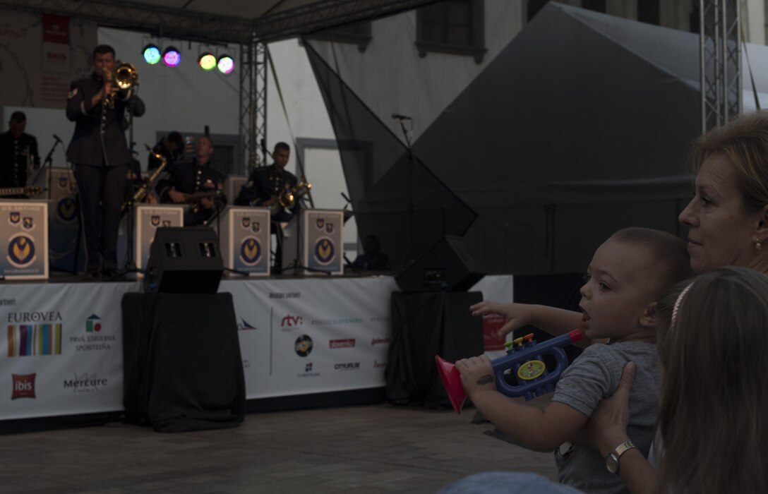 A child plays with a toy trumpet during a performance by the Ambassadors, U.S. Air Forces in Europe jazz band, for the 73rd anniversary of the Slovak National Uprising in Bratislava, Slovakia, Aug. 30, 2017. A U.S. band is invited each year to perform for the celebration, along with a variety of bands from multiple countries. The USAFE band, serves to increase cultural ties and to enhance the people-to-people relationship between the U.S. and Slovakia. (U.S. Air Force photo by Senior Airman Tryphena Mayhugh)