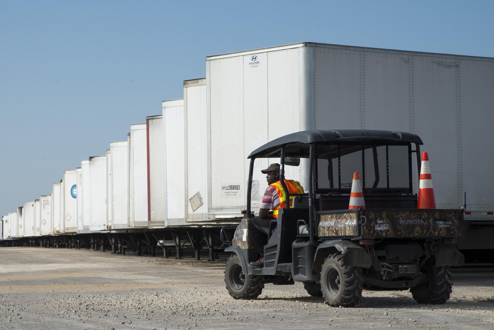 Worker in small vehicle facing left with semi trailers in a row behind him
