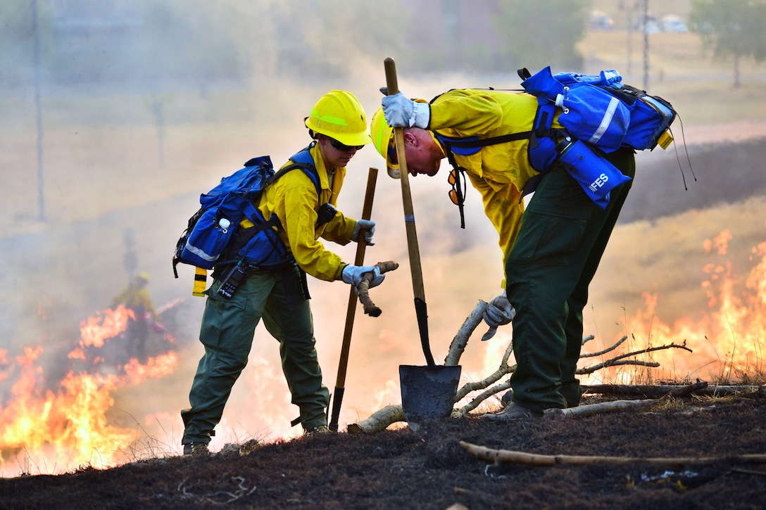 Oregon Army National Guardsmen work together to check charred branches