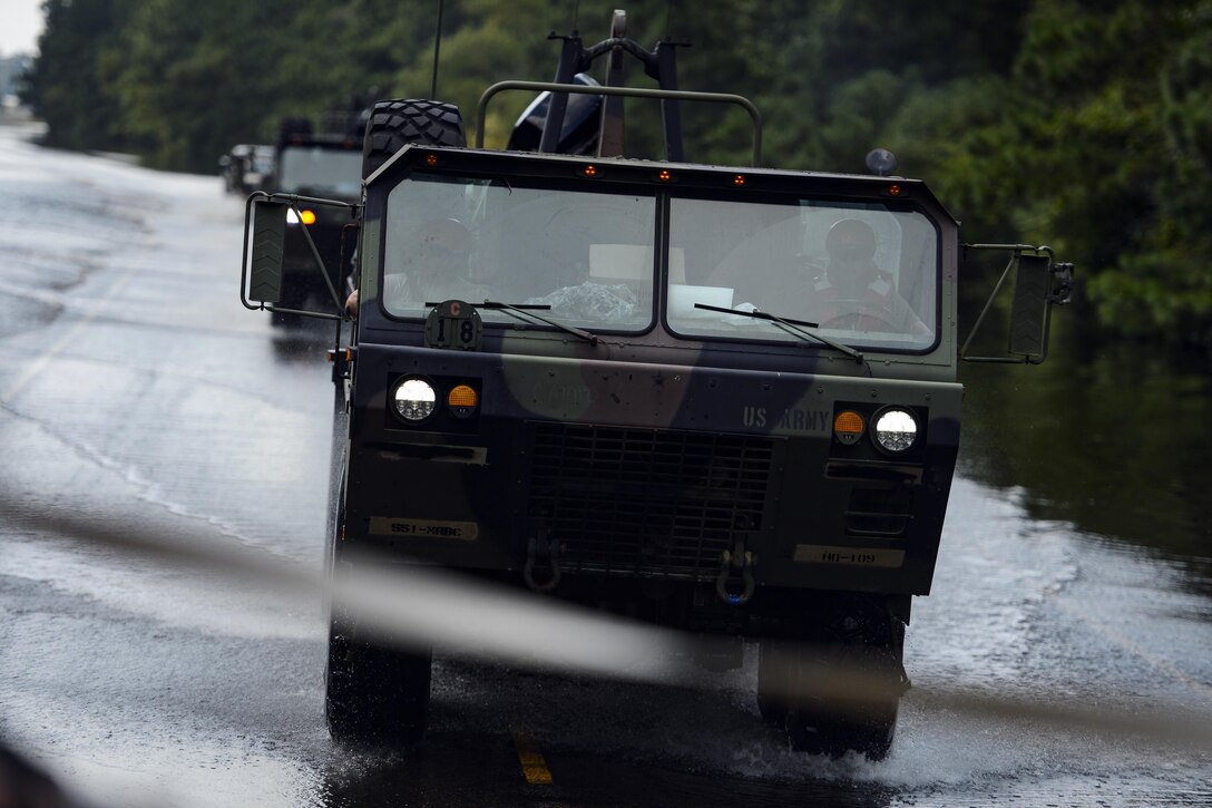 Military vehicles drive through flooded roads.