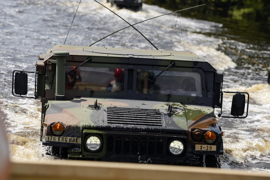 A military vehicle drives through water.