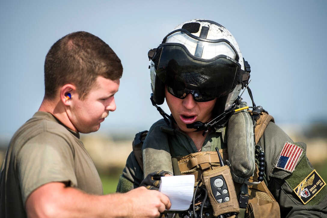 A sailor and a soldier look at a piece of paper and talk.