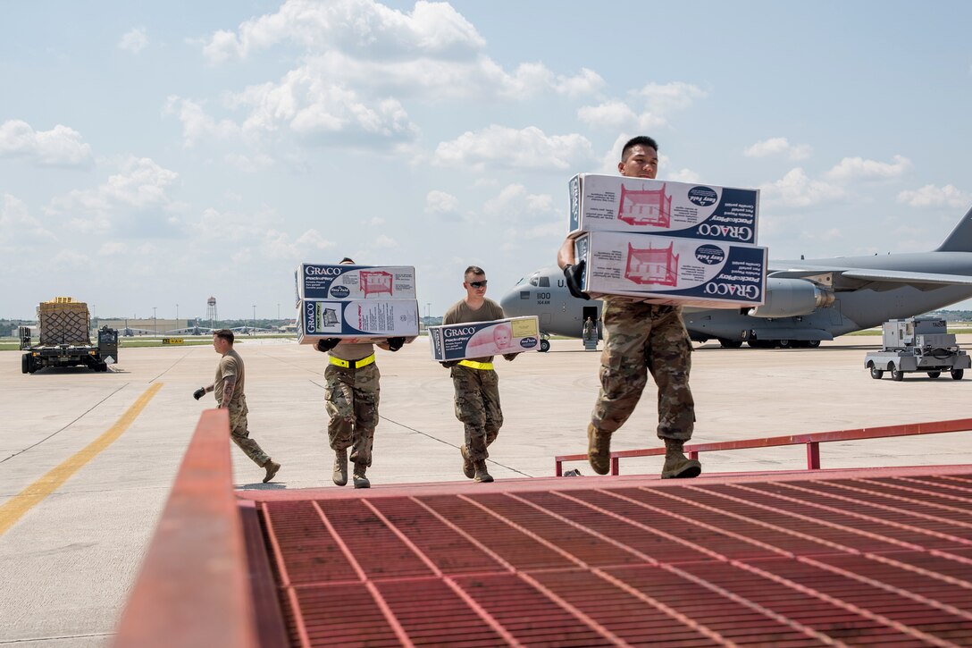 Soldiers carry boxes up a ramp.
