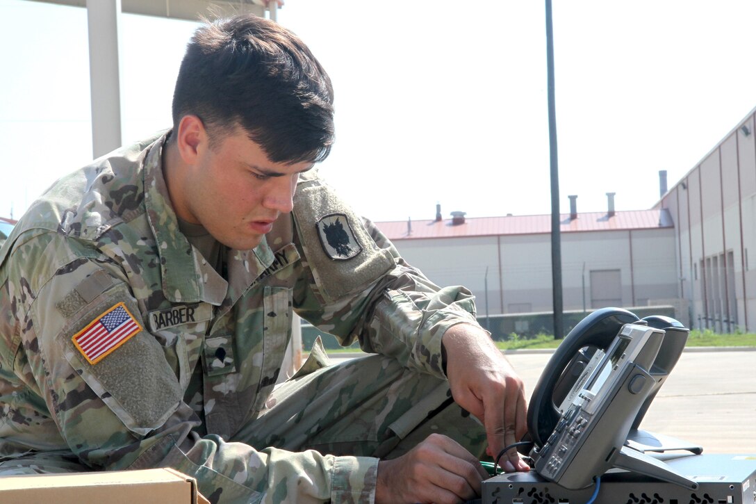 A soldier works on a phone.