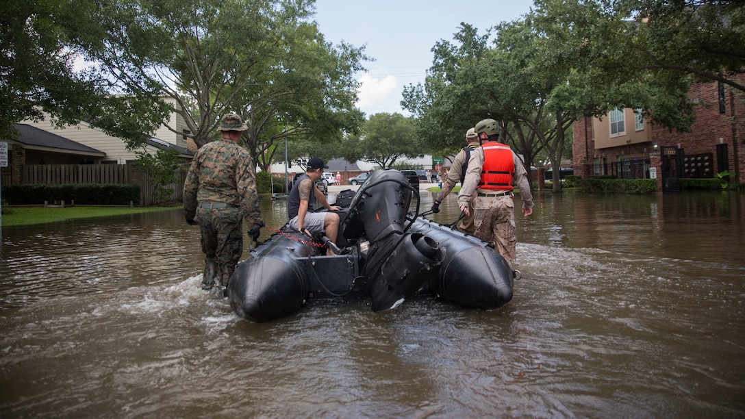 A Marine with Charlie Company, 4th Reconnaissance Battalion, 4th Marine Division, Marine Forces Reserve, along with a member of the Texas Highway Patrol and Texas State Guard, escort a man to higher ground, Houston, Texas, Aug. 31, 2017. Hurricane Harvey landed Aug. 25, 2017, flooding thousands of homes and displaced over 30,000 people.