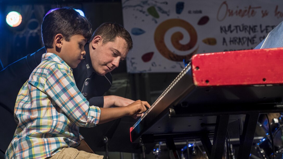 An airman plays the piano with a young boy after a concert in Slovakia.