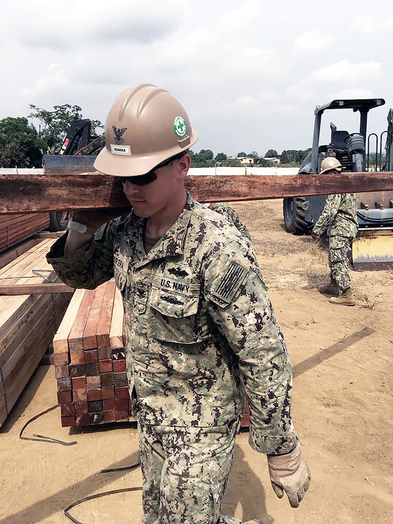 Navy Petty Officer 2nd Class James Herrera with Naval Mobile Construction Battalion 1 offloads lumber materials received for construction of a multipurpose building project in Douala, Cameroon, in March. Lumber, gravel and electrical parts are among the many supplies DLA buys locally for troops stationed in Africa.