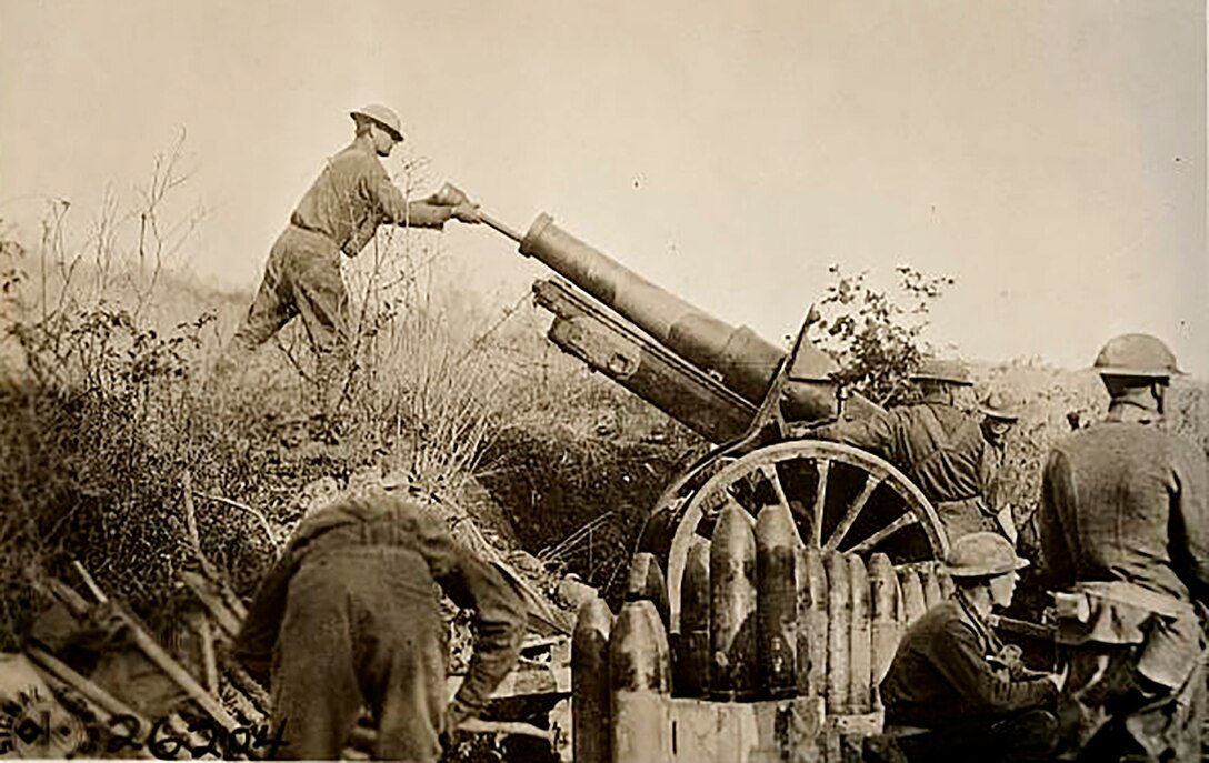 American soldiers from the 324th Field Artillery Regiment assist the 29th Infantry Division, in Cote de Roche, France, in loading the barrel of a camouflaged 155 mm Howitzer (circa 1917 or 1918).