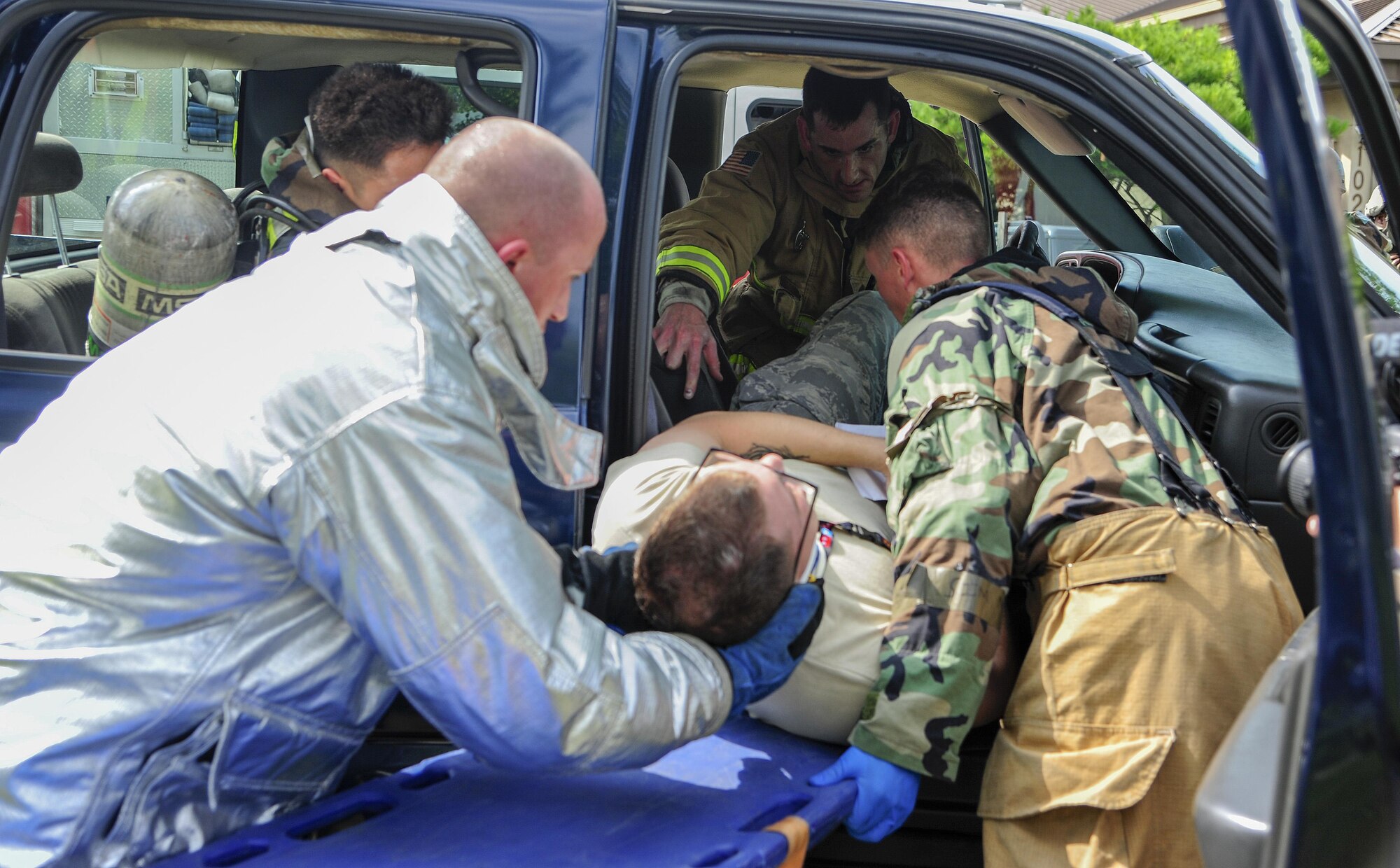 U.S. Air Force Airmen assigned to the 8th Civil Engineer Squadron fire department, remove a victim from a simulated car accident from the passenger seat onto a long spine backboard for transportation during training exercise Beverly Pack 17-3, at Kunsan Air Base, Republic of Korea, Aug. 22, 2017. This training test the medical and firefighting Airmen on responding to an accident and treating patients in high stress environments. (U.S. Air Force photo by Senior Airman Colby L. Hardin/Released)