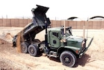 Marines use a dump-truck variation of the Medium Tactical Vehicle Replacement at Camp Bastion, Helmand Province, Afghanistan, to level the ground and create a staging area for their equipment.