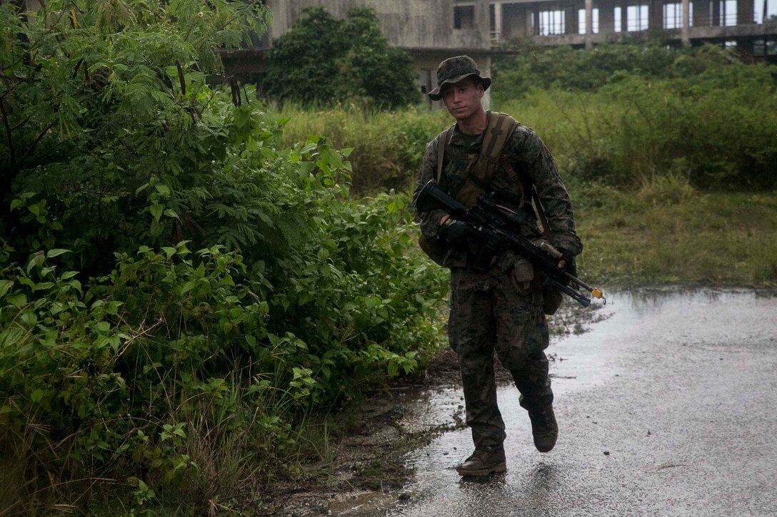 A Marine with Battalion Landing Team, 3rd Battalion, 5th Marines, patrols in the rain during Military Operations in Urbanized Terrain (MOUT) training at Andersen South Air Force Base, Guam, August 30, 2017. Marines with BLT 3/5 train regularly in different environments to maintain their readiness as the Ground Combat Element of the 31st Marine Expeditionary Unit. The 31st MEU partners with the Navy's Amphibious Squadron 11 to form the Bonhomme Richard Expeditionary Strike Group, providing a cohesive blue-green team capable of accomplishing a variety of missions across the Indo-Asia-Pacific region. (U.S. Marine Corps photo by Cpl. Amaia Unanue/Released)