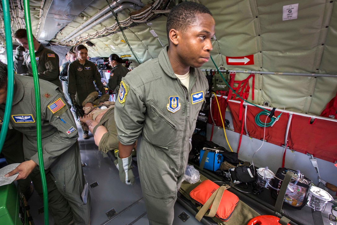 Senior Airman Marquis D. Waters, right, and Staff Sgt. Ana Nichols, center, carry a human simulator mannequin