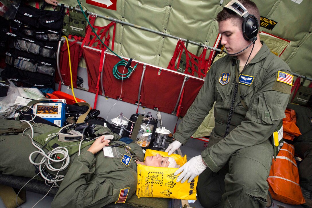 Senior Airman Jacob N. Patterson, right, stabilizes mock patient Staff Sgt. Ana Nichols, during an aeromedical evacuation training