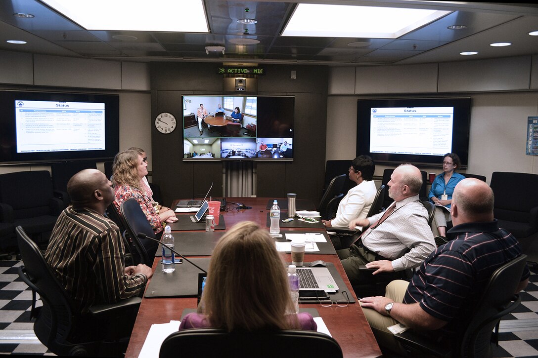 At Fort Belvoir, Virginia, senior leaders in DLA Information Operations listen as a team presents its project via video teleconference.