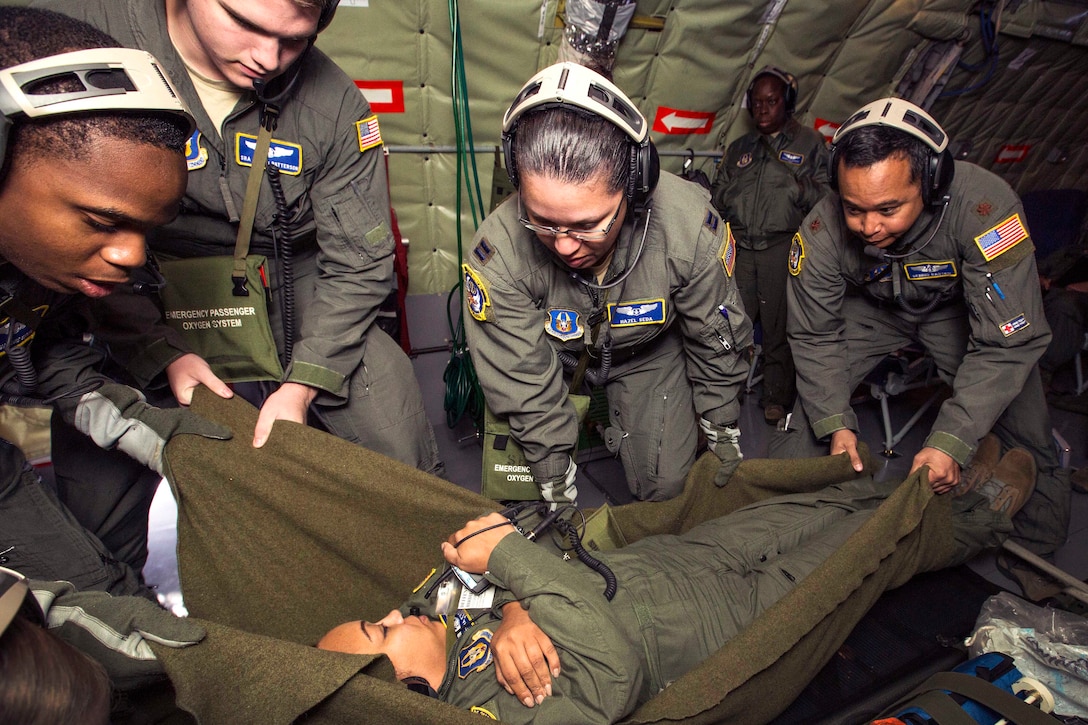 Airmen place a mock patient onto a litter