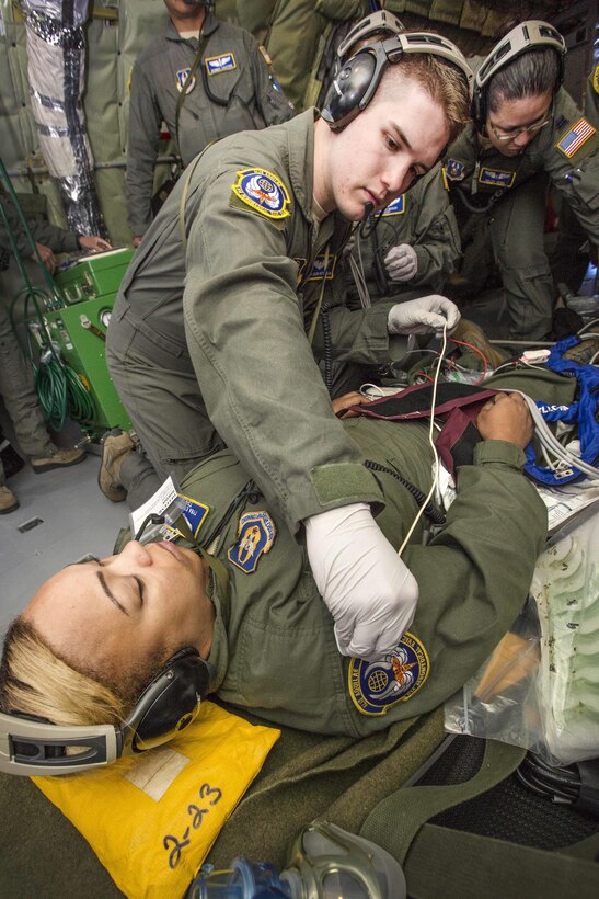 Senior Airman Jacob N. Patterson, kneeling, attaches electrocardiogram electrodes on mock cardiac arrest patient