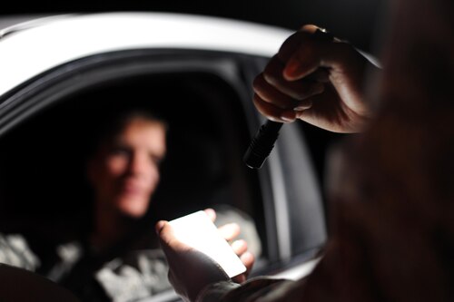 A 19th Security Forces Squadron Defender checks an ID before allowing a service member to enter the installation Aug. 29, 2017, at Little Rock Air Force Base, Ark. Before even entering the base, personnel are met by security forces Defenders who operate all entry and exit points, as well as patrol the base. (U.S. Air Force photo by Airman 1st Class Grace Nichols)