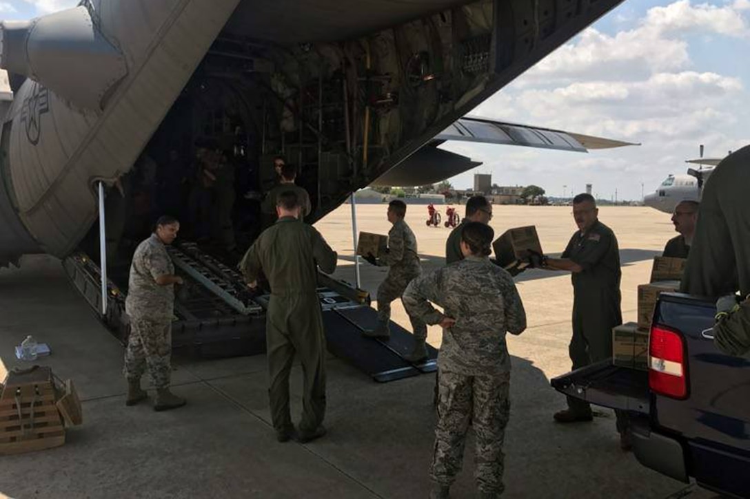 Guard members load relief supplies on a  C-130 aircraft.