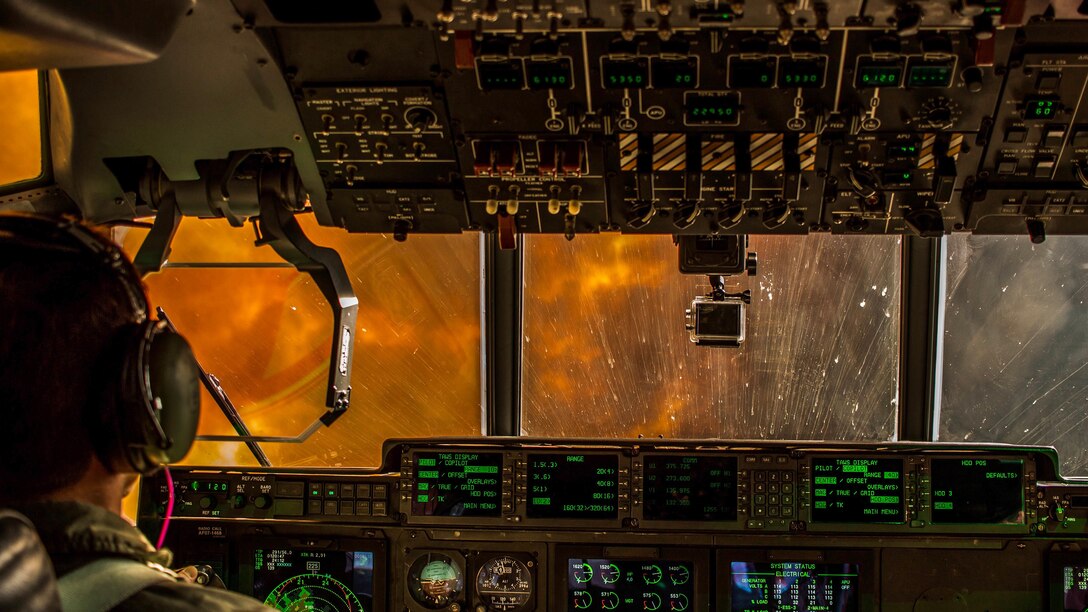 Flames and smoke cover an aircraft's windshield as an airman flies toward a fire.