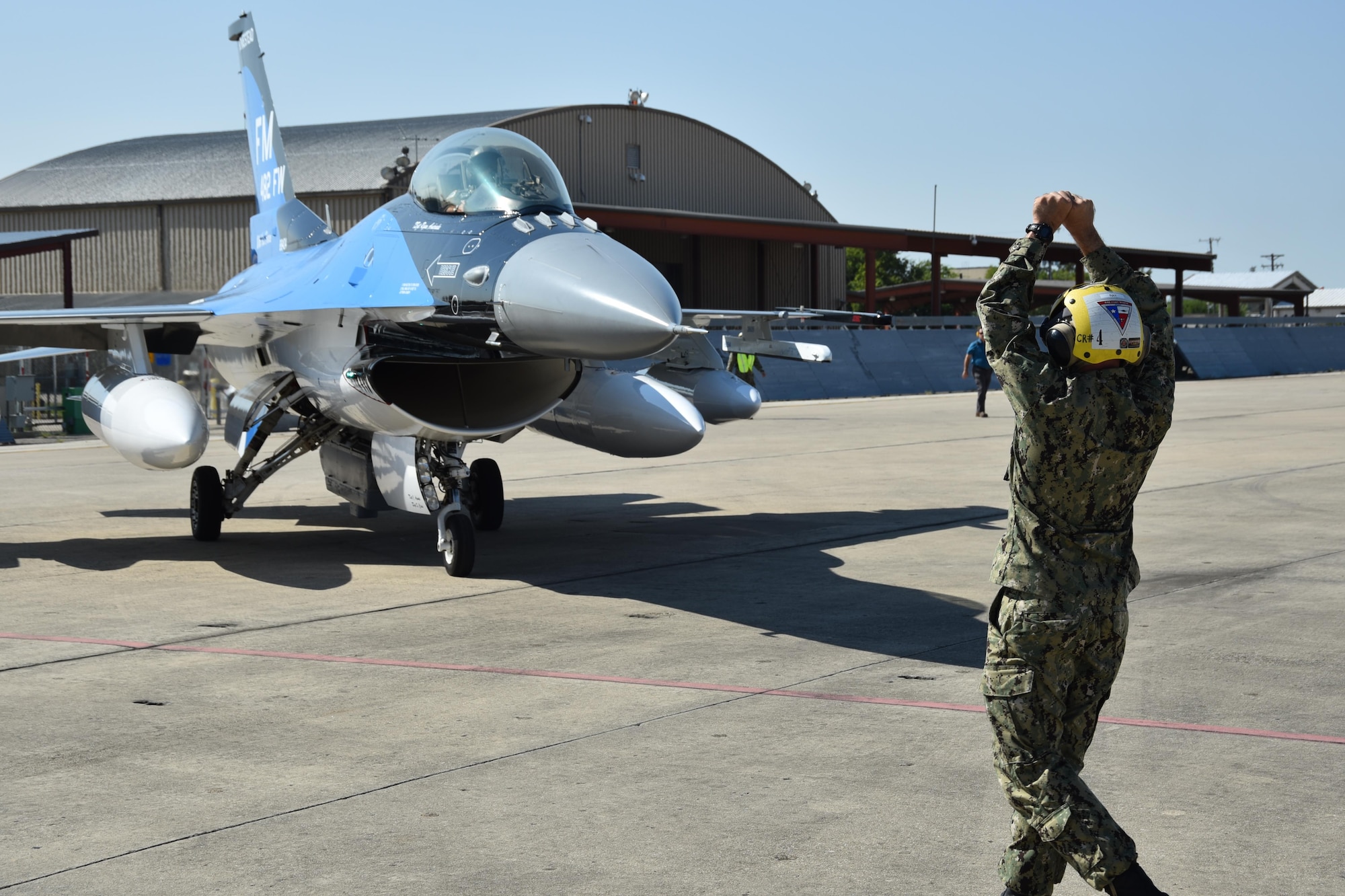 A sailor marshals an F-16 Fighting Falcon from Homestead Air Reserve Base, Fla., Sept. 6, 2017, at Naval Air Station Fort Worth Joint Reserve Base, Texas. The base serves as a safe haven for 14 military aircraft that relocated here due to Hurricane Irma's anticipated landfall in south Florida. (U.S. Air Force photo by Tech. Sgt. Charles Taylor)