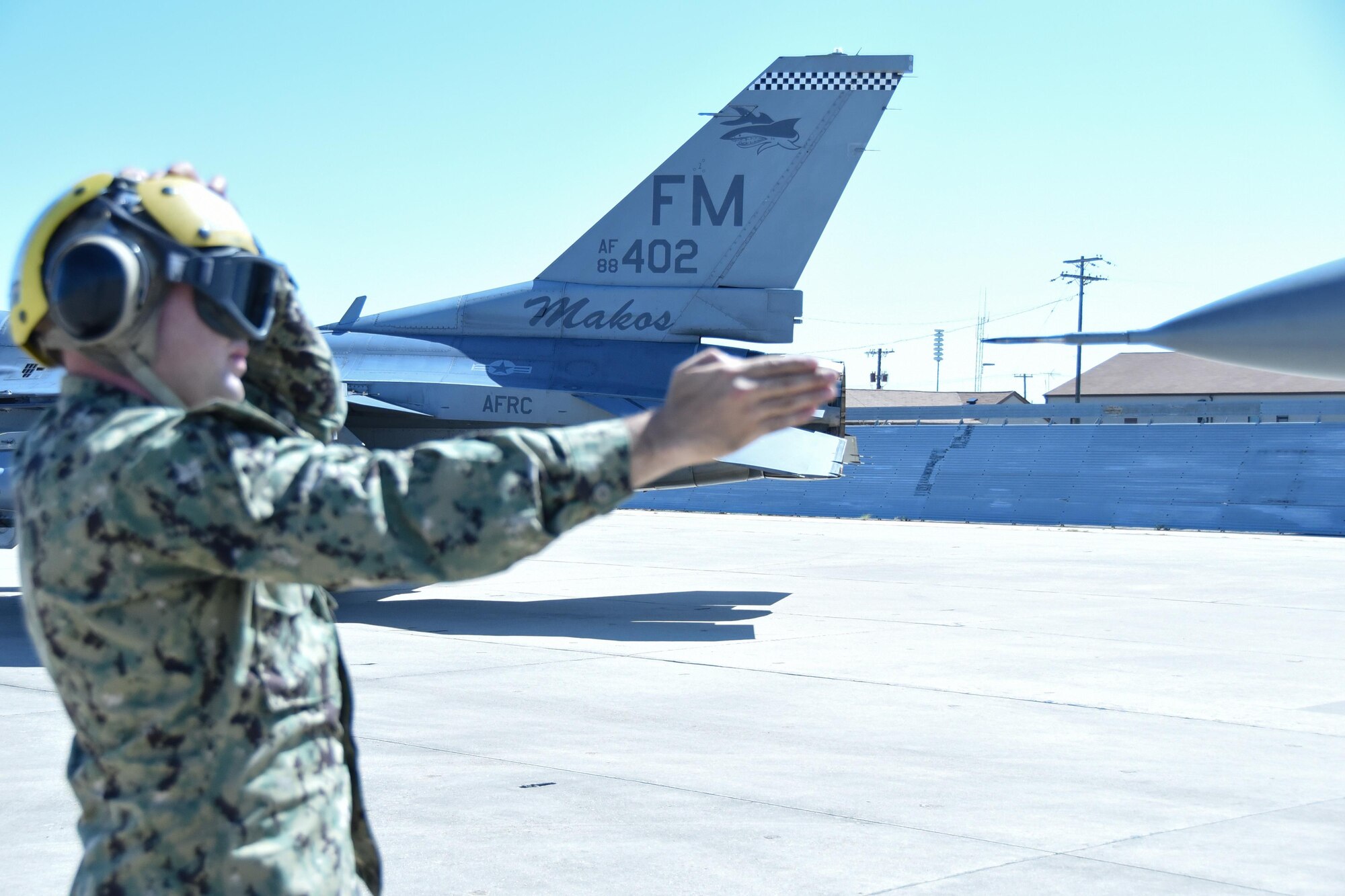A sailor marshals an F-16 Fighting Falcon from Homestead Air Reserve Base, Florida, Sept. 6, 2017, at Naval Air Station Fort Worth Joint Reserve Base, Texas. Fourteen aircraft relocated here today due to Hurricane Irma’s anticipated landfall. The base serves as a safe haven for military aircraft that are in the path of the hurricane. (U.S. Air Force photo by Maj. Candice Allen)