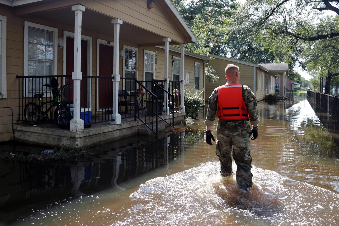 A soldiers walks through floodwaters near homes.