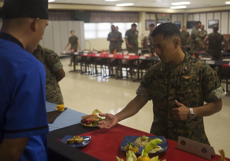 U.S. Marine Corps Col. Raul Lianez, the commanding officer of Marine Corps Base Hawaii (MCBH), observes the display of meals during the Chef of the Quarter cook-off competition at Anderson Hall aboard MCBH, August 23, 2017. After a series of evaluations to include a 50-question written test, an oral board and a uniform inspection, the U.S. Marines with top three highest combined scores were selected to be a part of the cook-off. The competitors used chicken, curry, cream cheese and kiwi fruit as items for their appetizer, entrée and desserts. (U.S. Marine Corps photo by Cpl. Zachary Orr)