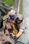 Staff Sgt. Justin Bender, 374th Operations Support Squadron survival, evasion, resistance and escape specialist, secures a simulated isolated person on a hoist as they are lifted into a UH-1N helicopter