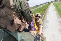 Staff Sgt. Justin Bender, 374th Operations Support Squadron survival, evasion, resistance and escape specialist, secures a simulated isolated person on a hoist as they are lifted into a UH-1N helicopter