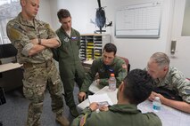 Crew members with the 459th Airlift Squadron check planned routes on a map