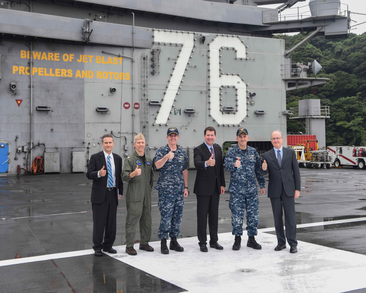 William F. Hagerty, U.S. ambassador to Japan, center, Rear Adm. Charles Williams, Commander, Task Force 70, right center, and Capt. Buzz Donnelly, commanding officer of the Navy's forward-deployed aircraft carrier, USS Ronald Reagan (CVN 76), left center, pose for a photo with other members of the tour group on the ship’s flight deck. Hagerty met with senior leadership and toured the ship during his first visit to Ronald Reagan since taking the office of U.S. ambassador to Japan in July. Ronald Reagan, the Navy’s forward-deployed aircraft carrier, provides a combat-ready force that protects and defends the collective maritime interests of the U.S. and its allies and partners in the Indo-Asia-Pacific region.