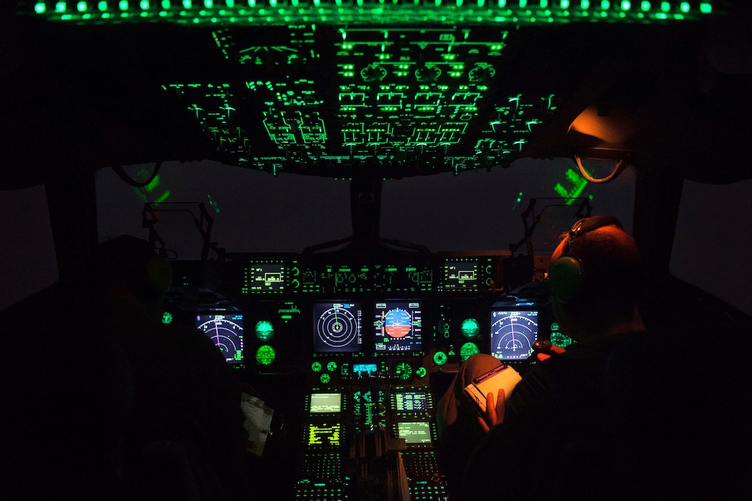 An Air Force C-17 Globemaster III cockpit lit up at night.
