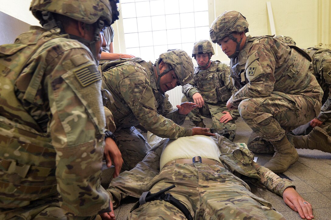 Soldiers provide medical aid to a mock casualty laying on the floor.