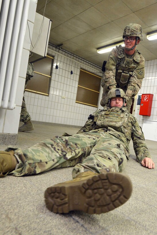 A soldier drags another solder across the ground.