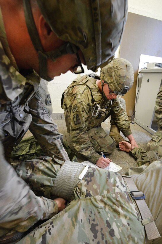 Two soldiers lean practice life saving skills.