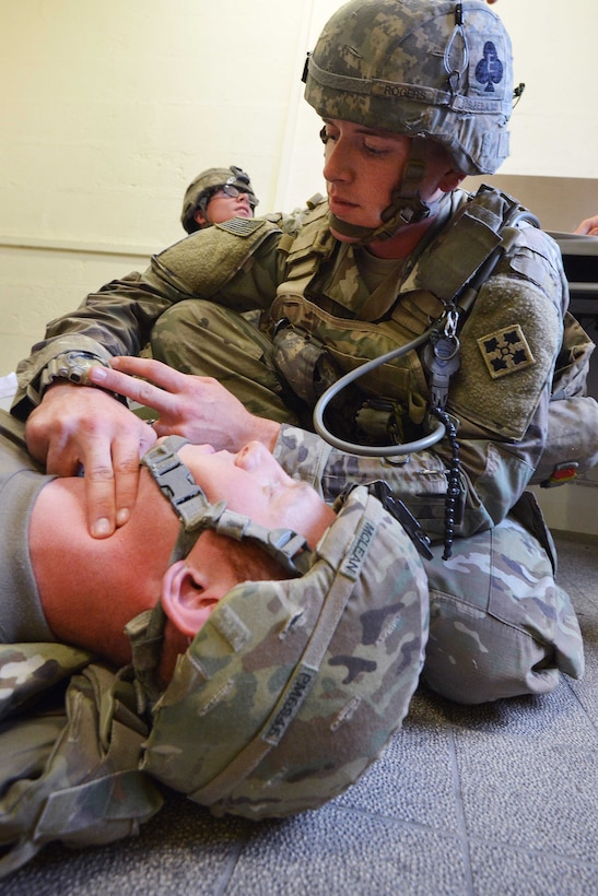 A soldier checks presses on the neck of another soldier to check the pulse.