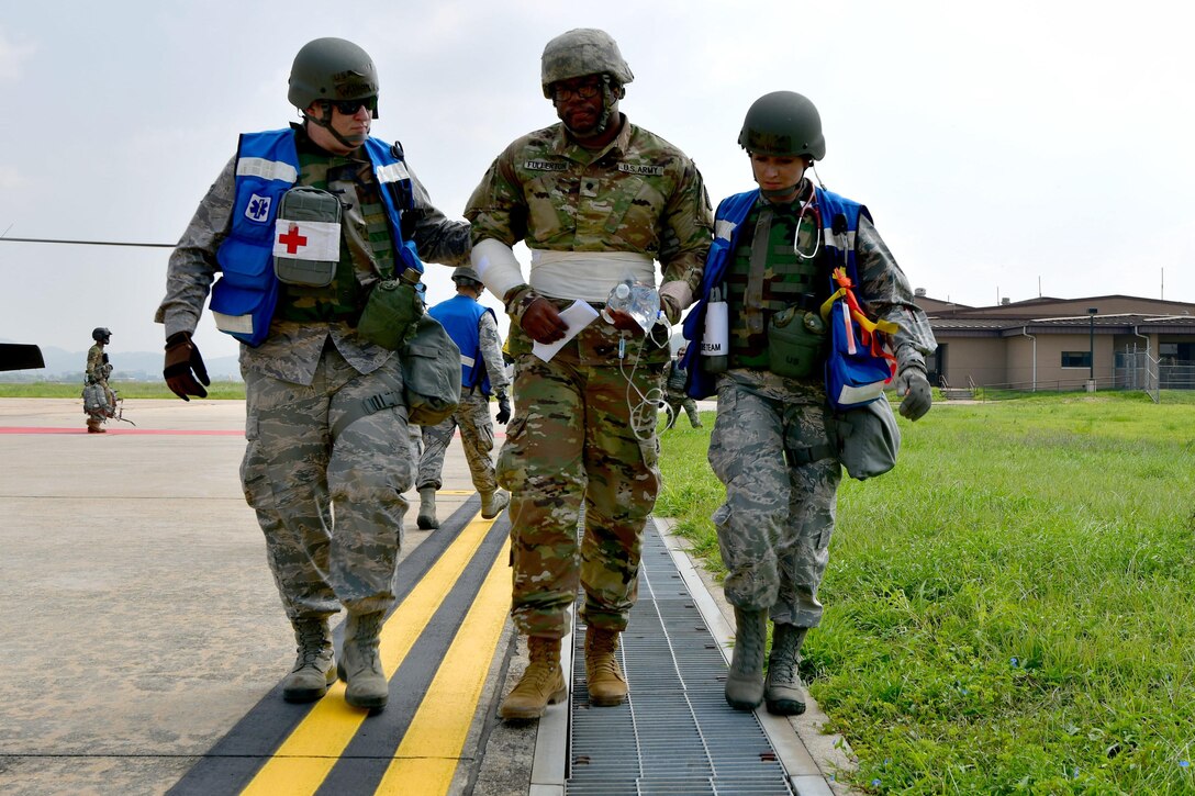 Two airmen walk with a soldier.