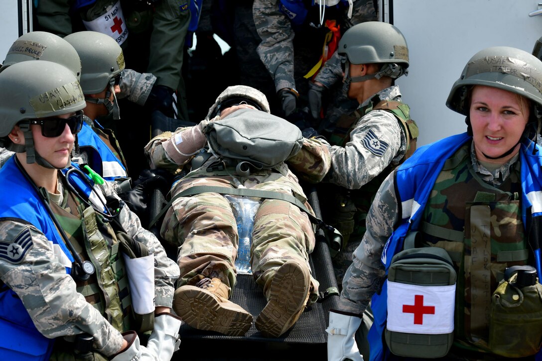 A group of Airmen lift a soldier on a stretcher.
