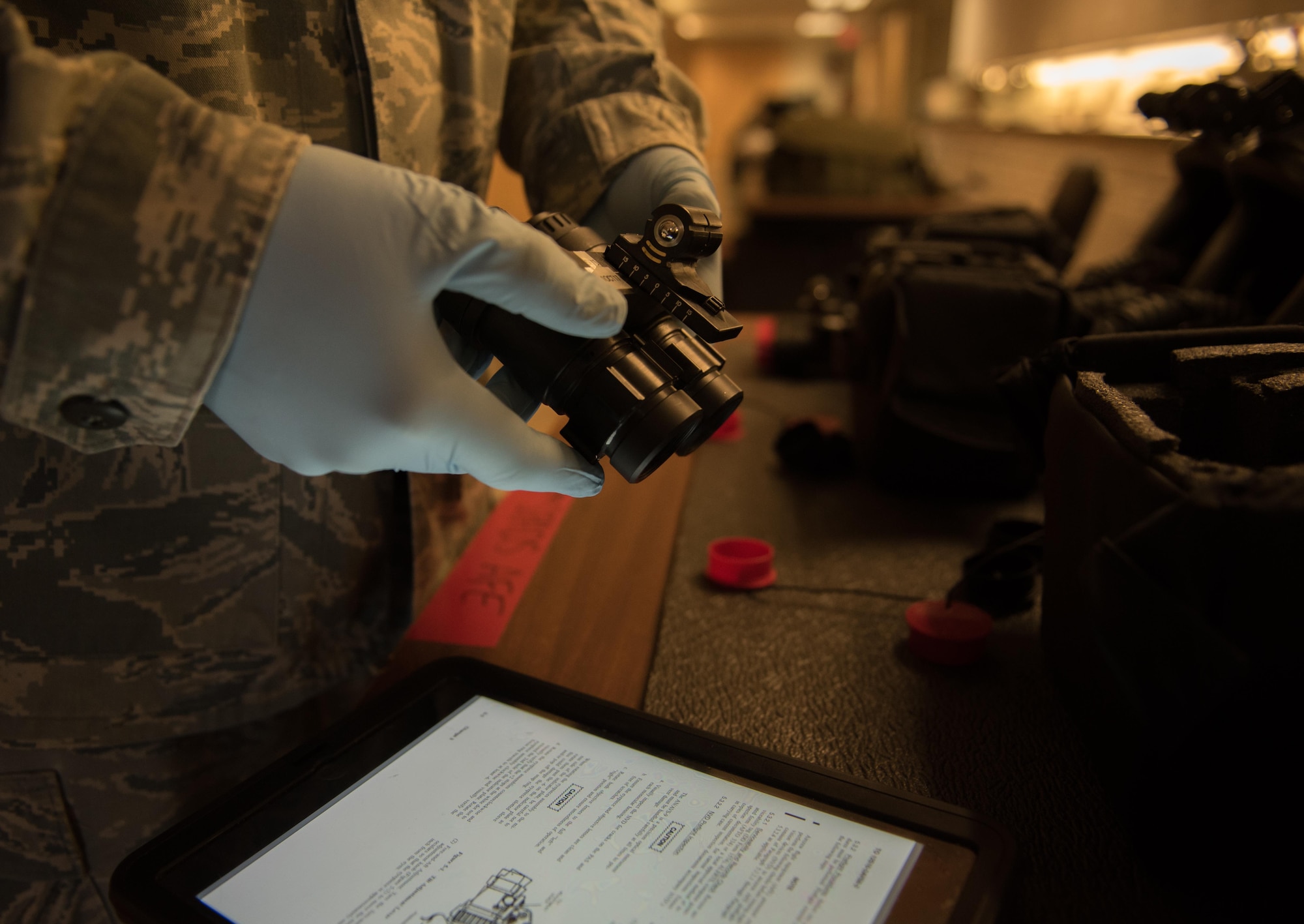 U.S. Air Force Staff Sgt. Robert Strayer, 1st Operational Support Squadron aircrew flight equipment technician, reviews the technical orders while inspecting night vision goggles for the night shift F-22 Raptor pilots during Red Flag 17-4 at Nellis Air Force Base, Nev., Aug. 24, 2017. The night vision goggles are used by the pilots during nighttime missions to increase their combat readiness. (U.S. Air Force photo by Staff Sgt. Carlin Leslie)