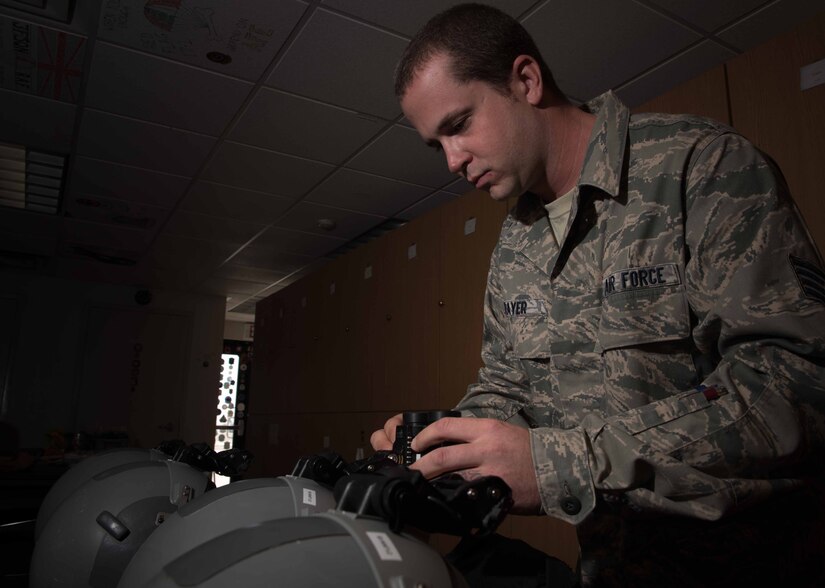 U.S. Air Force Staff Sgt. Robert Strayer, 1st Operational Support Squadron aircrew flight equipment technician, attaches night vision goggles to a pilot’s helmet, during Red Flag 17-4 at Nellis Air Force Base, Nev., Aug. 24, 2017. While at RF, pilots fly daytime mission and night time missions to help keep current in all combat scenarios. (U.S. Air Force photo by Staff Sgt. Carlin Leslie)